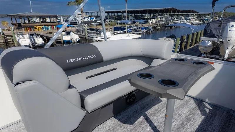 Slide: The Image of Bennington 21 S Swingback 2026: Sleek gray sofa with table and cup holders at the marina. - 9