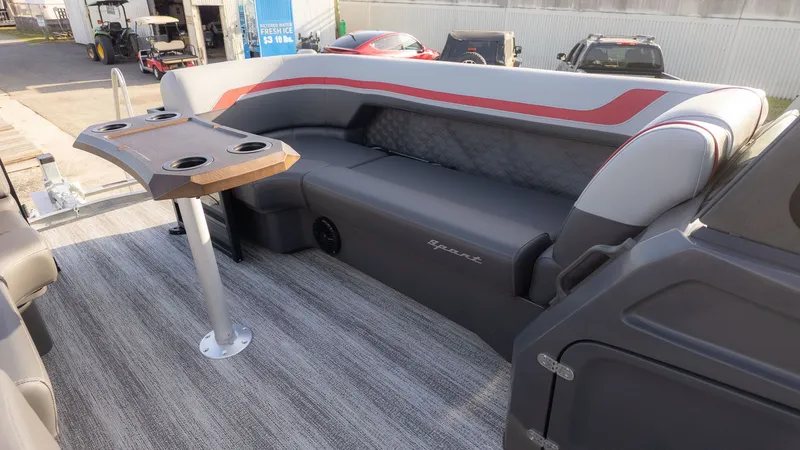 Slide: The Image of Interior of a Bennington 22 S Swingback with gray and red seating and a table with cup holders. - 8
