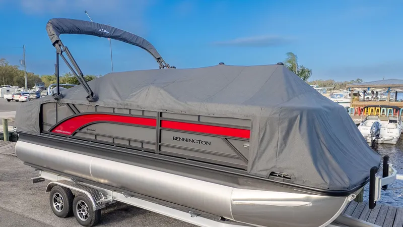 Slide: The Image of A Bennington 22 S Swingback pontoon boat with a gray cover on a trailer. - 19