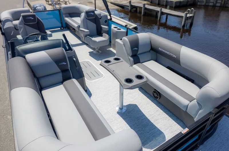 Slide: The Image of Bennington 22 S STERN RADIUS 2026: Spacious pontoon boat with luxurious seating and table, docked by the water. - 14
