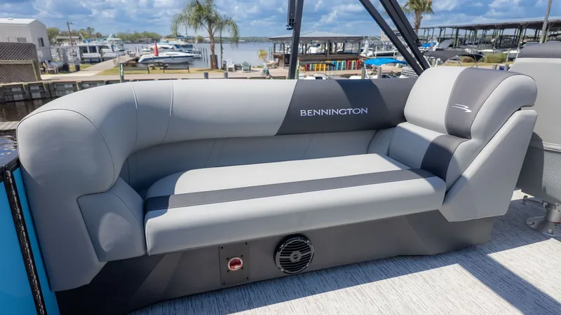 Slide: The Image of Bennington 22 S STERN RADIUS 2026: Sleek gray sofa on a boat with a marina in the background. - 7