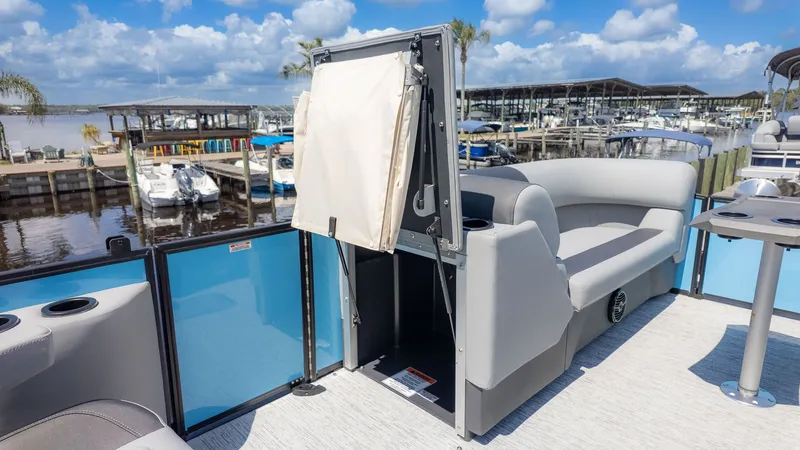 Slide: The Image of A modern pontoon boat with gray seating and a folding table, docked at a marina. - 11