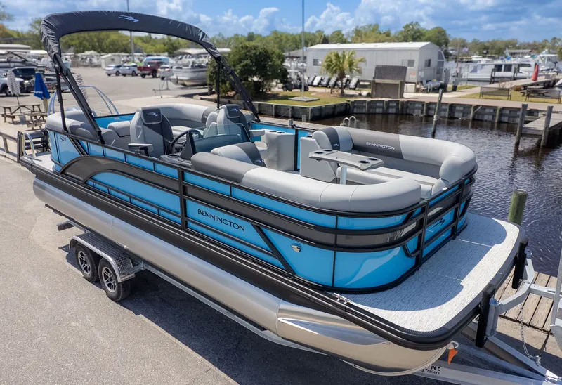 The Image of A 2026 Bennington 22 S STERN RADIUS pontoon boat on a trailer at a marina. - 1
