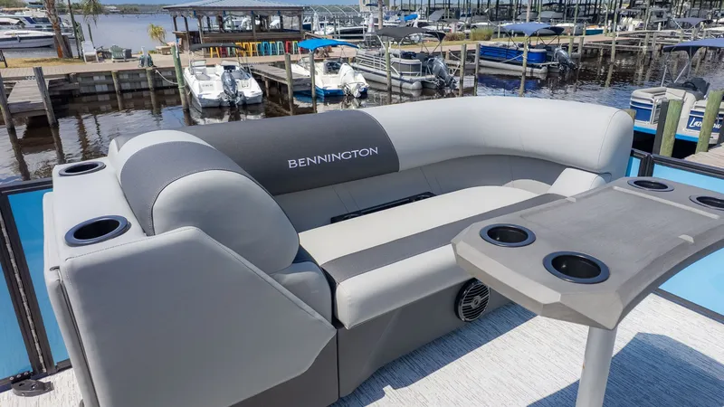 Slide: The Image of The image shows the stern of a Bennington pontoon with gray seating and a table with cup holders. - 15
