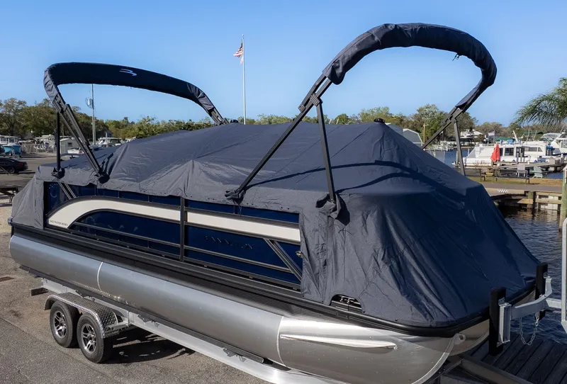 Slide: The Image of A Bennington pontoon boat with a cover on a trailer, parked at a marina. - 22