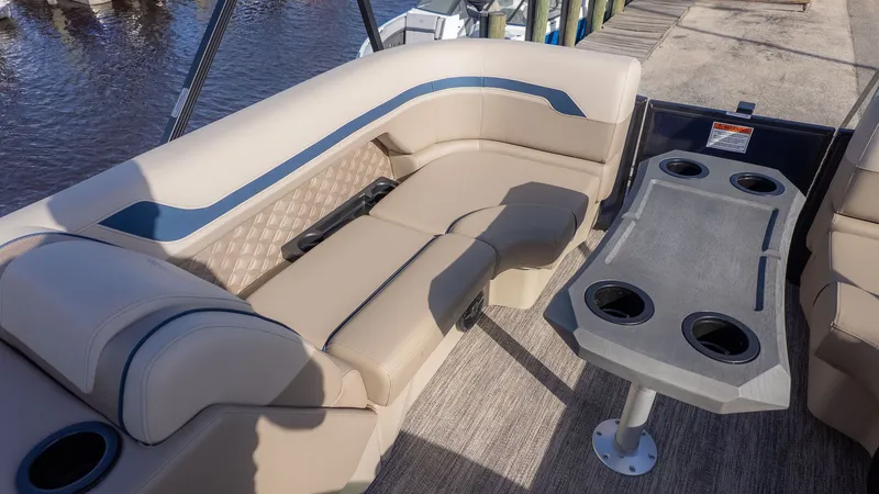 Slide: The Image of The image shows the interior of a 2026 Bennington 22 S STERN RADIUS boat with beige seating and a table with cup holders. - 12