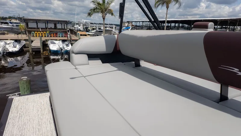 Slide: The Image of The image shows the deck of a Bennington 22 S Swingback boat with gray upholstery. A marina and palm trees are visible in the background. - 4