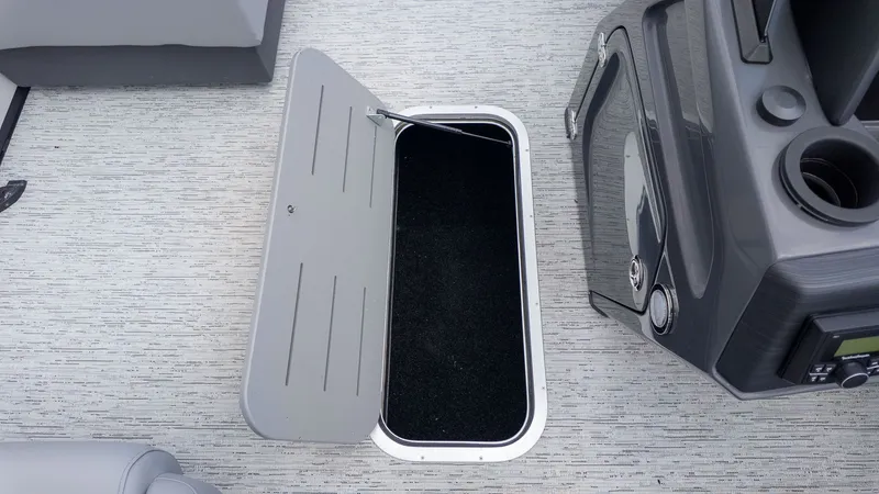 Slide: The Image of An open storage compartment lid on a boat with gray flooring. - 7