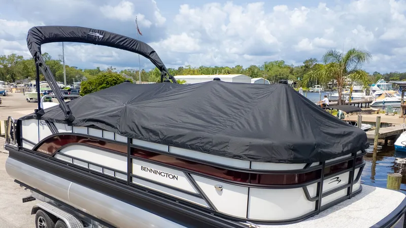 Slide: The Image of Bennington 22 S Swingback pontoon boat with cover, parked at a marina, surrounded by other boats. - 17