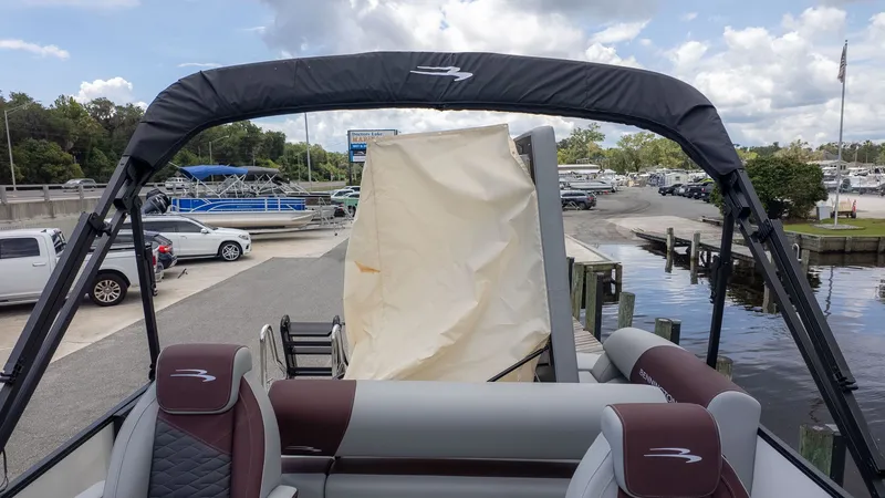 Slide: The Image of Bennington 22 S Swingback pontoon boat at dock with Bimini top and cushioned seats. - 4