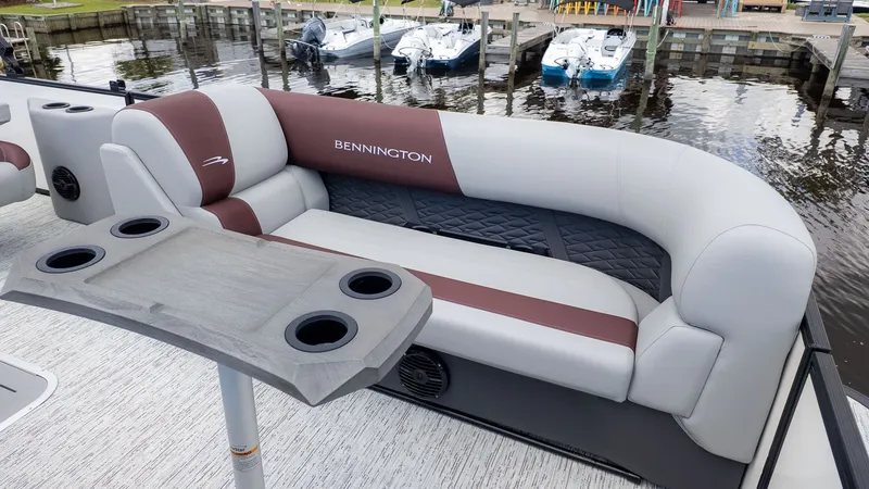 Slide: The Image of A sleek Bennington pontoon boat with a comfortable bench seat and cup holders, docked by the water. - 8