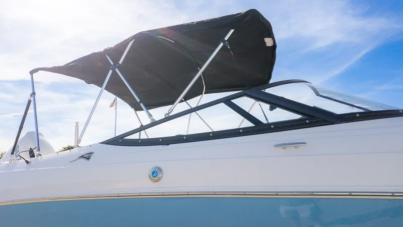 The Image of A modern boat with a blue hull and black sunshade under a clear sky. - 1
