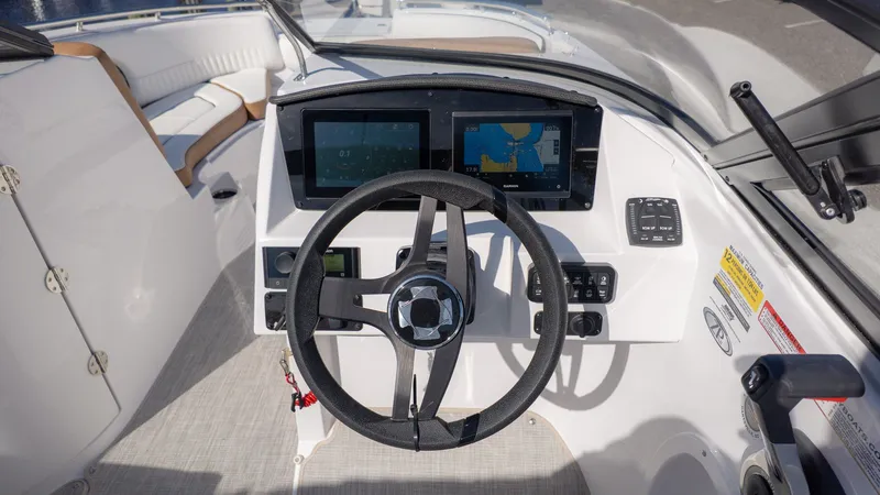 Slide: The Image of The image shows the helm of a Stingray 231 DC boat with two screens and a steering wheel. - 25