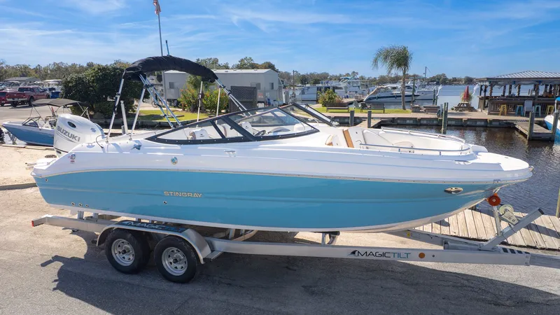 Slide: The Image of A 2026 Stingray 231 DC boat on a trailer, parked in a marina area. - 27