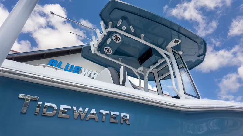 The Image of A blue Tidewater 210 LXF boat with a T-top in front of a building. - 1