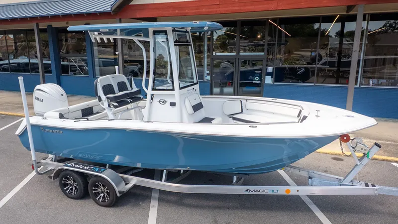 Slide: The Image of A blue and white Tidewater 210 LXF boat on a trailer parked in front of a building. - 19