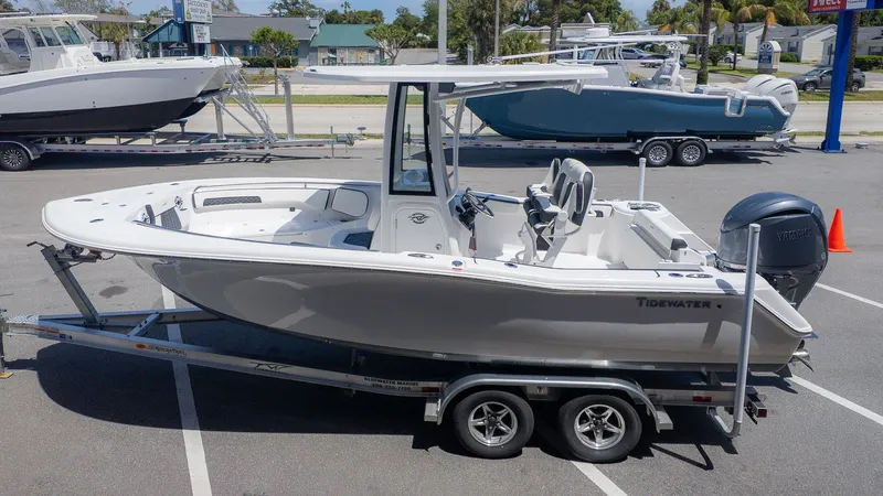 The Image of Tidewater 220 CC Adventure from 2026 on a trailer in a parking lot, with other boats in the background. - 1