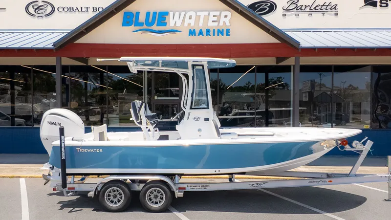 The Image of Tidewater 2210 Carolina Bay 2027 on a trailer in front of a boat dealership. - 1