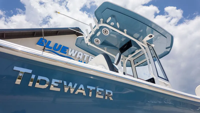 The Image of A blue Tidewater boat with a T-top in front of a building labeled "BLUEWATER." - 1