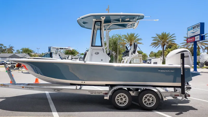 The Image of A 2027 Tidewater 2210 Carolina Bay boat on a trailer in a sunny parking lot. - 1