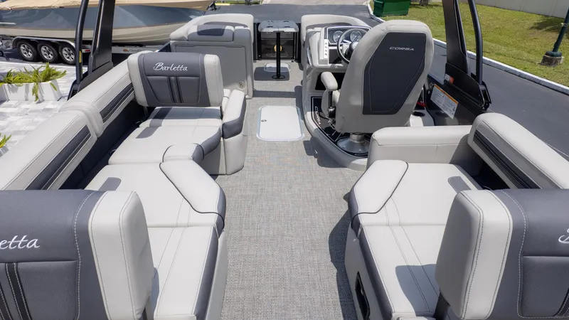 Slide: The Image of The image shows the interior of a Barletta Corsa 23M pontoon boat with gray upholstery and a helm. - 9