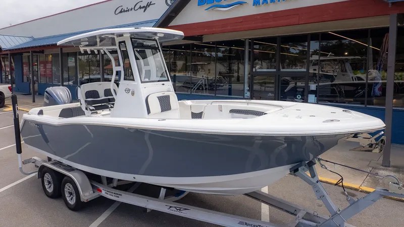 The Image of A gray Tidewater 232 LXF boat from 2027 sits on a trailer outside a store. - 1