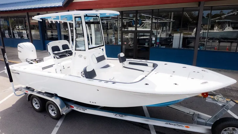 The Image of A white Tidewater 2300 Carolina Bay boat on a trailer in front of a building. - 1