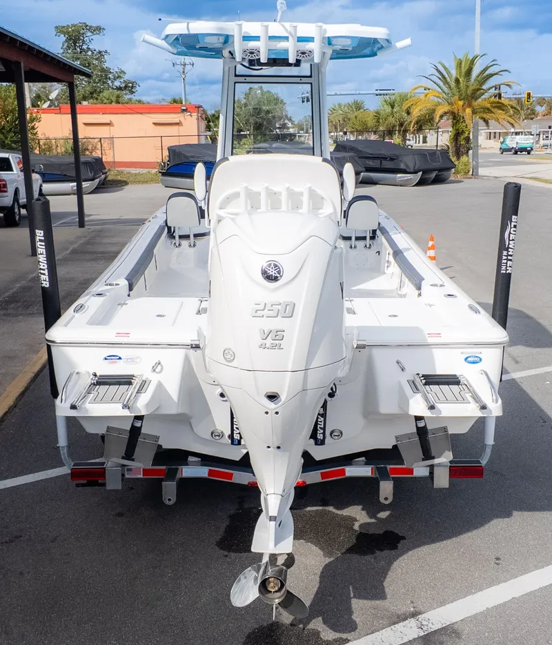 Slide: The Image of The image shows a white boat on a trailer in a parking lot. It features an outboard motor and a T-top cover. - 3