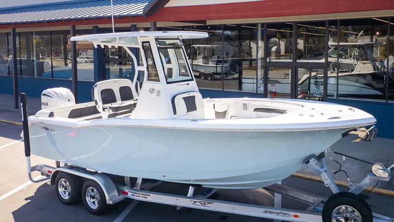 The Image of A white Tidewater 232 LXF boat on a trailer in front of a building with blue windows. - 1