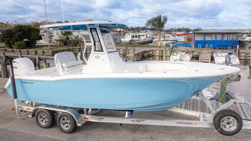 Slide: The Image of A light blue Tidewater 232 CC Adventure boat on a trailer, parked at a marina. - 24