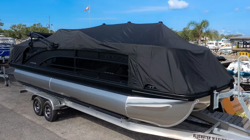 Slide: The Image of A 2026 Bennington 24 M Stern Lounge pontoon boat, covered, on a trailer at a marina. - 23