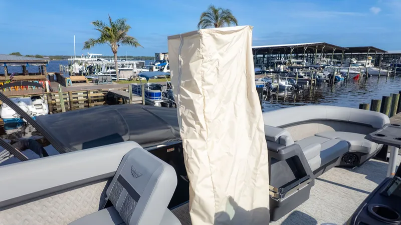 Slide: The Image of A Bennington 24 M Stern Lounge pontoon boat docked, featuring gray seating and a cover. - 9