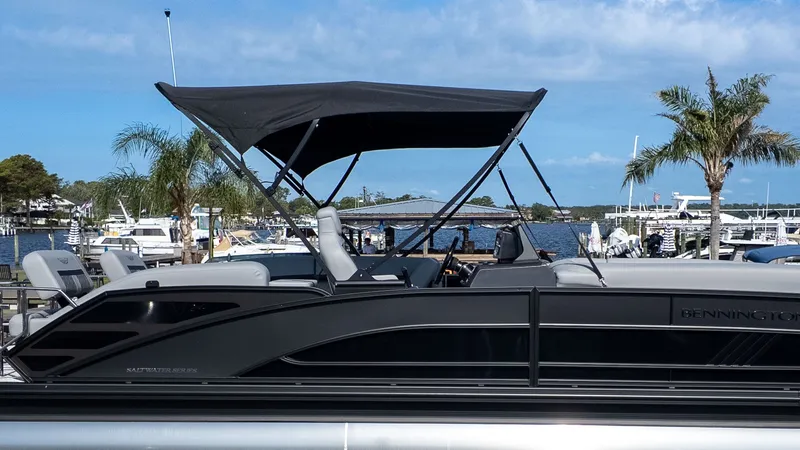 Slide: The Image of 2026 Bennington 24 M Stern Lounge with black sunshade, docked with palm trees in the background. - 22