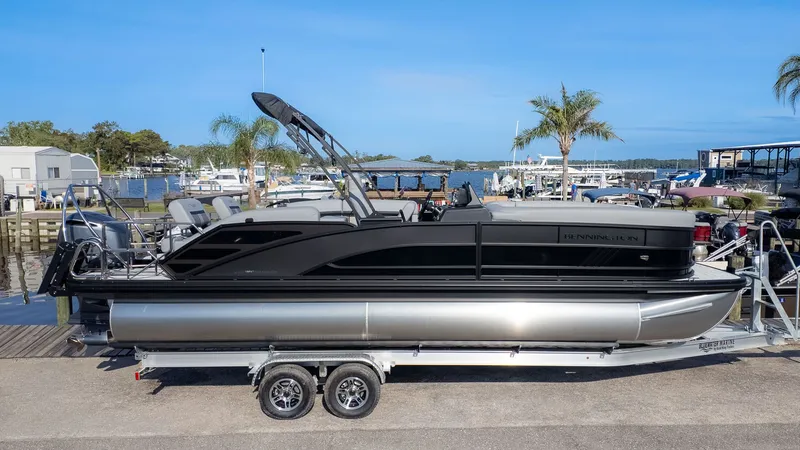 Slide: The Image of Bennington 24 M Stern Lounge 2026 on a trailer by the water. - 21