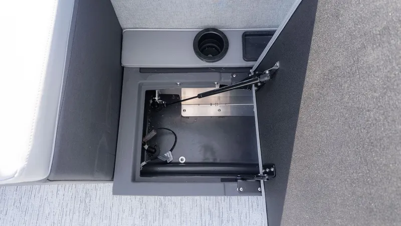 Slide: The Image of An open storage compartment on a Bennington 24 M Stern Lounge boat, featuring gray upholstery and a cup holder. - 4