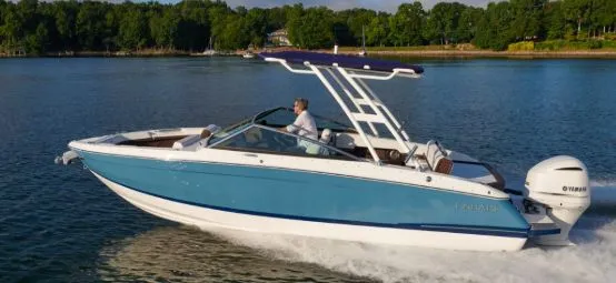 The Image of A 2026 Cobalt R4 boat cruising on a calm lake with a wooded shoreline in the background. - 1
