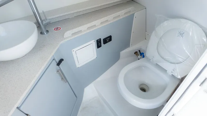 Slide: The Image of The image shows a boat toilet with gray cabinets and a white sink. - 25