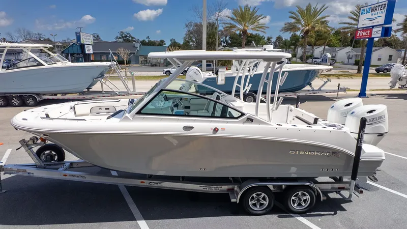 Slide: The Image of A modern Stingray 259 DC boat on a trailer, parked in an outdoor showroom. - 3