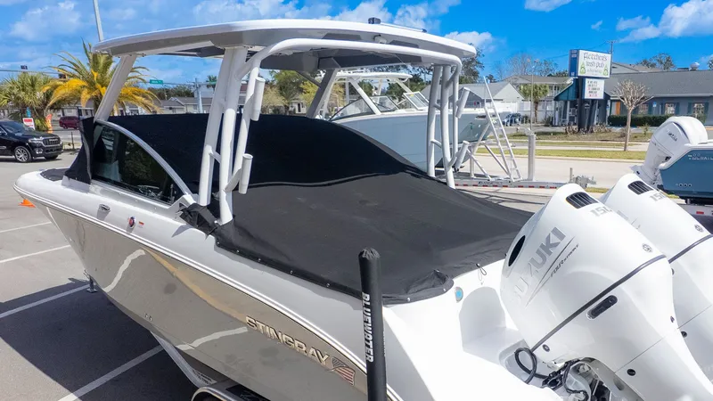 The Image of A modern Stingray 259 DC with a black cover and twin Suzuki engines, parked on a trailer. - 1