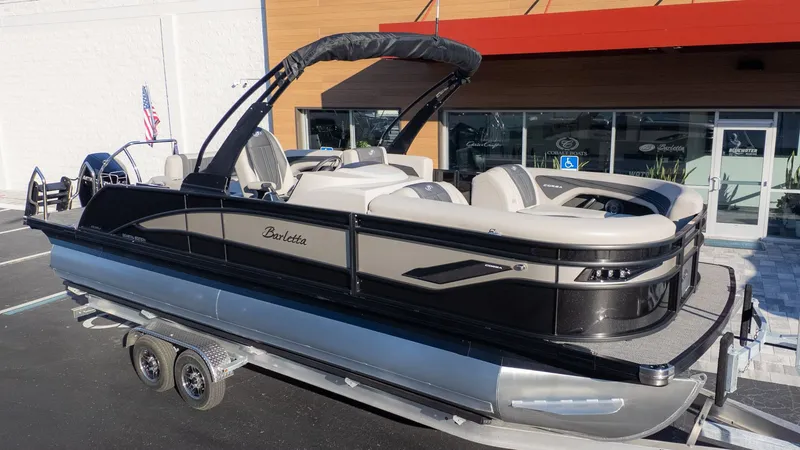 Slide: The Image of A sleek 2026 Barletta Corsa X23U pontoon boat on a trailer in front of a building. - 26
