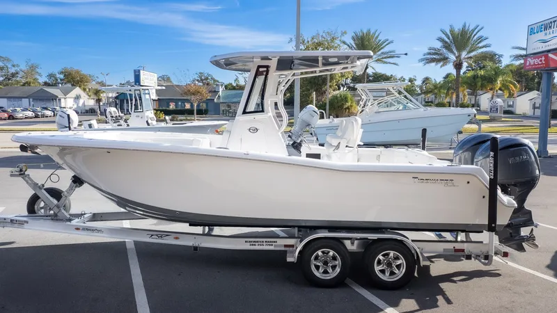 The Image of A white Tidewater 256 CC Adventure boat on a trailer, parked in a lot. - 1