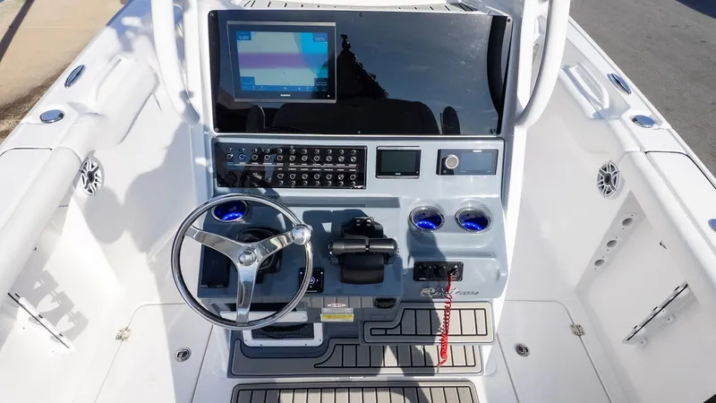Slide: The Image of The image shows the helm of a Tidewater 256 CC Adventure boat. It features a modern design with a large screen, steering wheel, and various controls. - 15