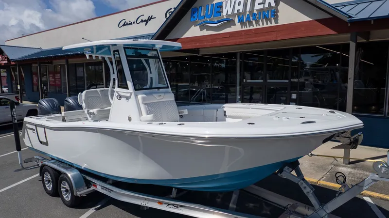 The Image of A white Tidewater 256 CC Adventure boat on a trailer outside a marine store. - 1