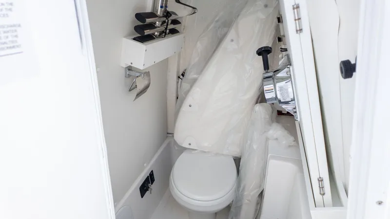 Slide: The Image of The image shows a compact boat toilet with white walls and a small sink. - 9