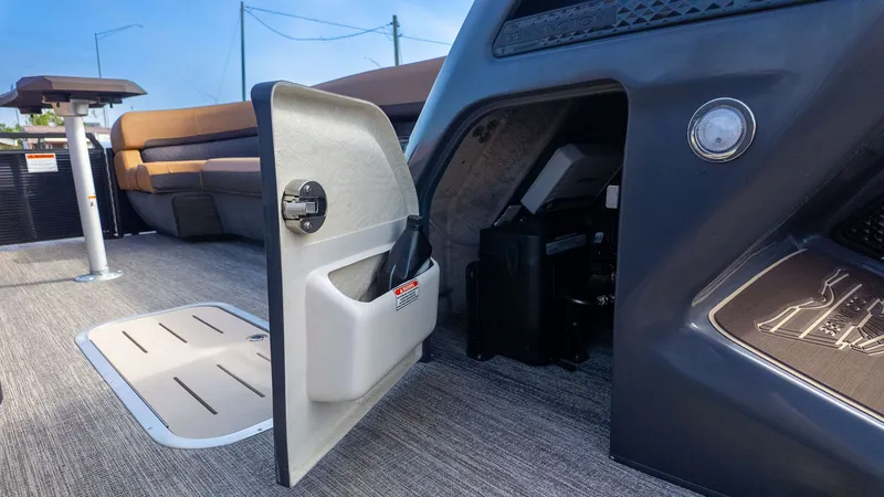 Slide: The Image of An open storage compartment on a boat with gray carpeting and brown seating. - 20