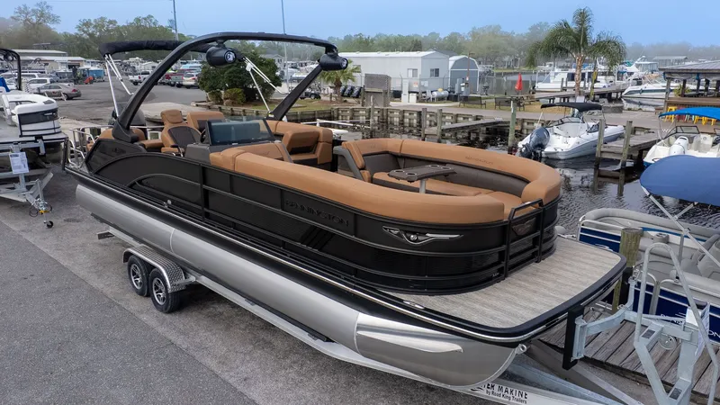 The Image of A luxurious pontoon boat with brown seating and black railing, on a trailer at the marina. - 1