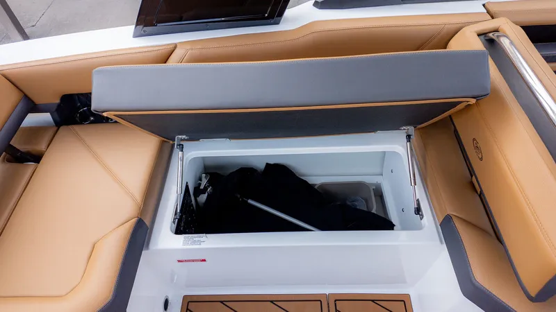 Slide: The Image of The image shows the storage compartment of a 2026 Cobalt R6B boat with beige upholstery. - 13