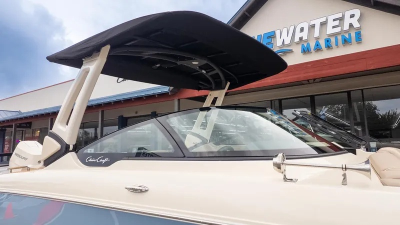 The Image of A Chris-Craft Sportster 28 boat in front of a marine store. It features a black sunshade. - 1