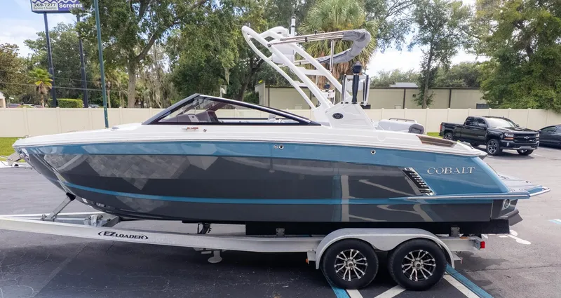 Slide: The Image of 2026 Cobalt R6 Surf on a trailer, featuring a blue and gray hull, parked outdoors. - 3