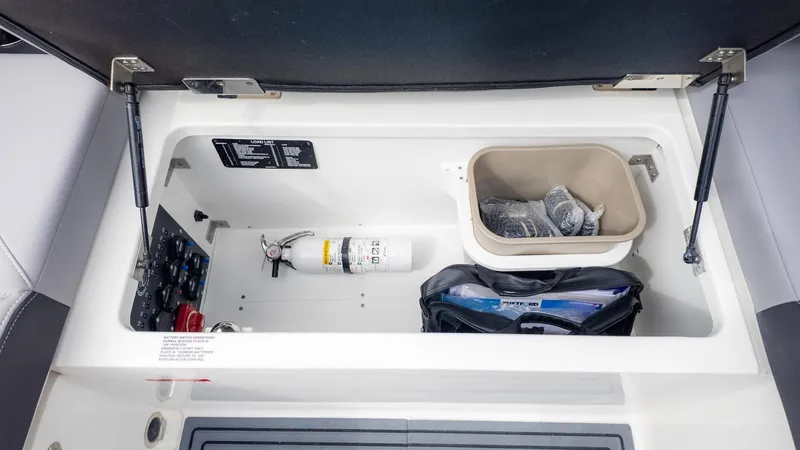 Slide: The Image of An open storage compartment on a Cobalt R6 Surf boat with a fire extinguisher and accessories. - 16